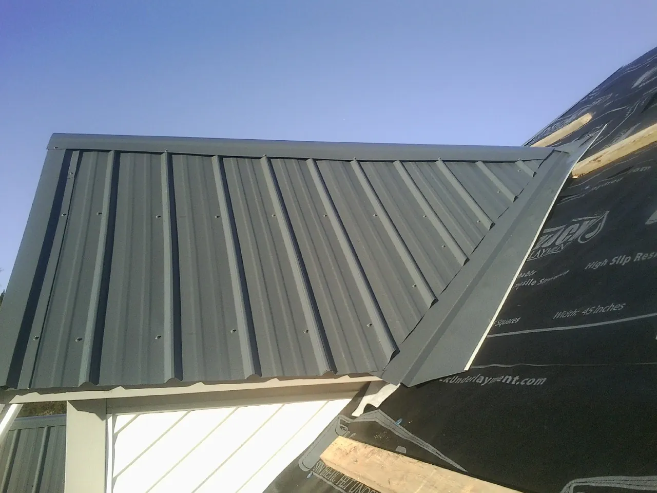Gray metal roof panels going on over a garage gable in Stephenson