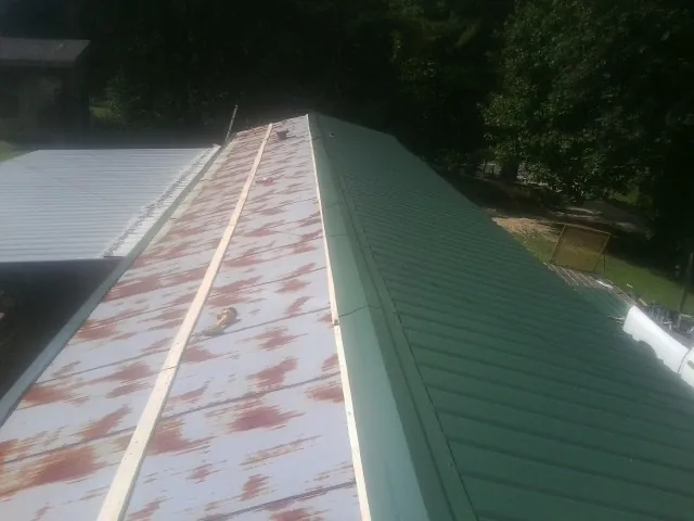 Old rusted panels beside newly installed green metal roofing — Wind Damage Roof Repair by Roofing Brothers in Stephenson