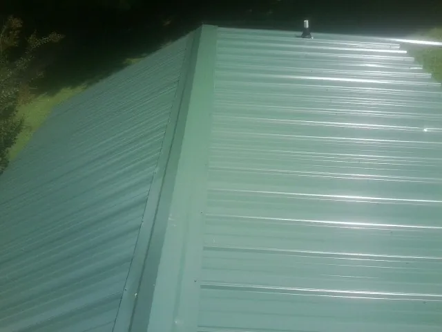 New green metal panels meeting at the ridge of a roof — Flat Roof Repair work by our crew in Stephenson