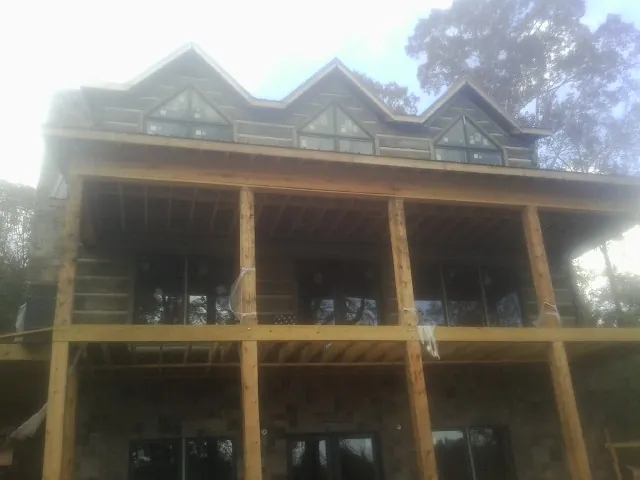 Dormers and porch framing on a large log home under construction — Roof Coating work by our crew in Stephenson