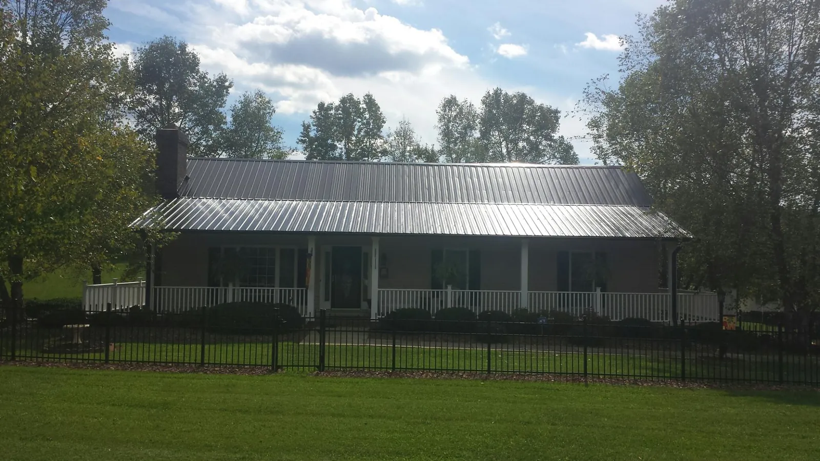Gray metal roof on a brick ranch with a full width front porch — Gutter Guard Installation work by our crew in Stephenson