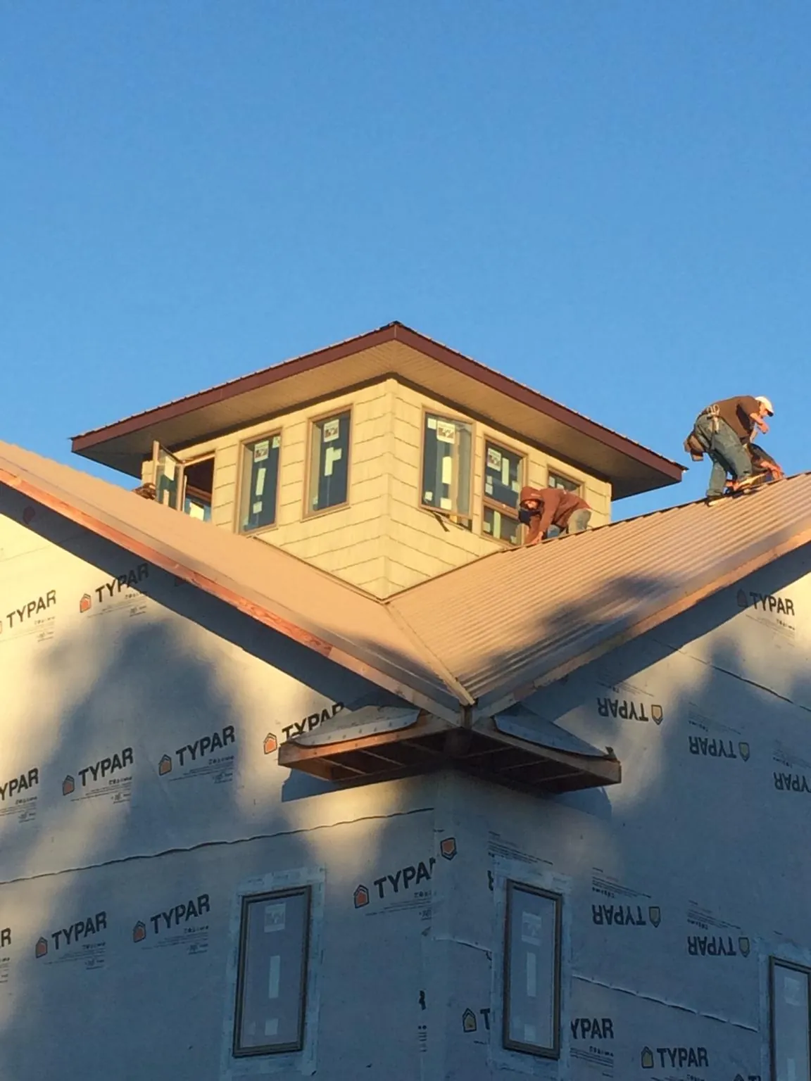 Roofers working around a rooftop cupola on a new metal roof at sunset — Roof Waterproofing in Stephenson by Roofing Brothers